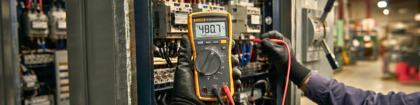 Técnico electricista midiendo tensión con multímetro Fluke en cuadro eléctrico industrial